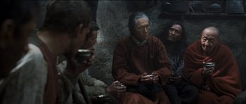 Movie still from “The Way Back” (2010), directed by Peter Weir – A group of men sitting around a stone wall; Medium shot, High angle