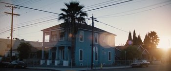 Movie still from “The Way Back” (2020), directed by Gavin O'Connor – A blue building with a palm tree in the background; Extreme Wide shot, Low angle