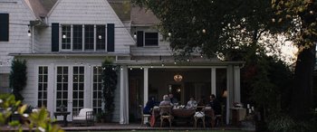 Movie still from “The Way Back” (2020), directed by Gavin O'Connor – A group of people sitting at a table outside of a house; Extreme Wide shot, High angle