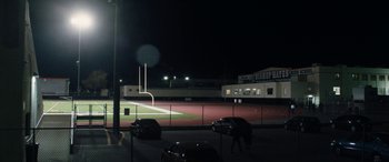 Movie still from “The Way Back” (2020), directed by Gavin O'Connor – A view of a baseball field at night from a parking lot; Extreme Wide shot, High angle