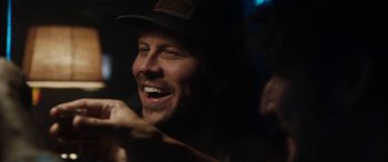 Movie still from “The Way Back” (2020), directed by Gavin O'Connor – A person wearing a hat; Close Up shot, Over the shoulder angle