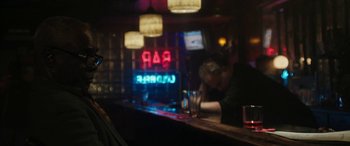 Movie still from “The Way Back” (2020), directed by Gavin O'Connor – A man sitting at a bar with a drink in front of him; Medium shot, Over the shoulder angle