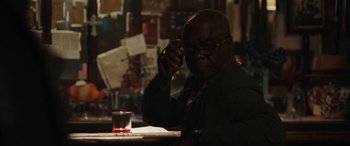 Movie still from “The Way Back” (2020), directed by Gavin O'Connor – A man sitting at a table with a drink in front of him; Close Up shot, Over the shoulder angle