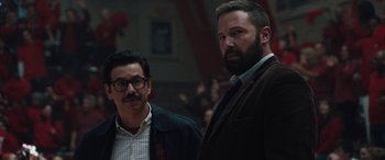 Movie still from “The Way Back” (2020), directed by Gavin O'Connor – Two men standing next to each other in front of a crowd; Medium shot, Over the shoulder angle