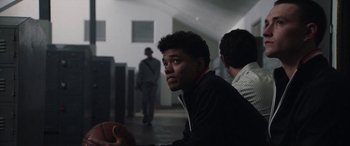 Movie still from “The Way Back” (2020), directed by Gavin O'Connor – A young man holding a basketball in front of other men; Close Up shot, Over the shoulder angle