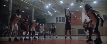 Movie still from “The Way Back” (2020), directed by Gavin O'Connor – A group of young men playing a game of basketball; Wide shot, Low angle