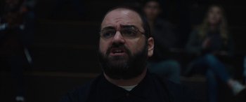 Movie still from “The Way Back” (2020), directed by Gavin O'Connor – A man with a goatee and glasses in a dark room; Close Up shot, Low angle