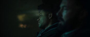 Movie still from “The Way Back” (2020), directed by Gavin O'Connor – A young man is looking into the distance in the dark; Close Up shot, Over the shoulder angle