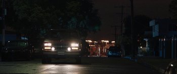 Movie still from “The Way Back” (2020), directed by Gavin O'Connor – A car driving down a street at night with headlights on; Wide shot, Over the shoulder angle