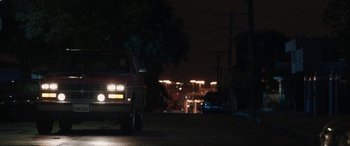 Movie still from “The Way Back” (2020), directed by Gavin O'Connor – A truck driving down a street at night with lights on; Wide shot, Over the shoulder angle