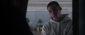 Movie still from “The Way Back” (2020), directed by Gavin O'Connor – A young man looking out of a window at the beach; Close Up shot, Over the shoulder angle