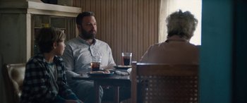 Movie still from “The Way Back” (2020), directed by Gavin O'Connor – A man sitting at a table with a glass of beer; Medium shot, Over the shoulder angle