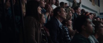 Movie still from “The Way Back” (2020), directed by Gavin O'Connor – A group of people sitting in the stands watching a basketball game; Medium shot, Over the shoulder angle