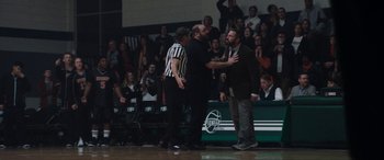 Movie still from “The Way Back” (2020), directed by Gavin O'Connor – A referee and two men are arguing in front of a crowd of people; Wide shot, Over the shoulder angle