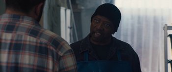 Movie still from “The Way Back” (2020), directed by Gavin O'Connor – An older man wearing an apron talking to another man in a plaid shirt; Close Up shot, Over the shoulder angle