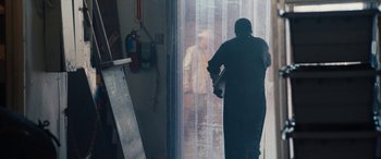 Movie still from “The Way Back” (2020), directed by Gavin O'Connor – A man standing in front of a window looking out; Wide shot, Low angle