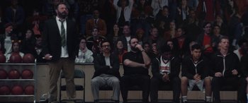 Movie still from “The Way Back” (2020), directed by Gavin O'Connor – A group of people sitting in a room watching a basketball game; Wide shot, High angle