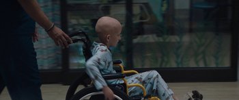 Movie still from “The Way Back” (2020), directed by Gavin O'Connor – A young child in a wheelchair in a hospital room; Medium shot, Over the shoulder angle