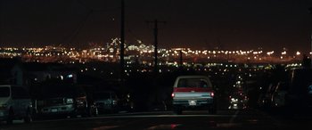 Movie still from “The Way Back” (2020), directed by Gavin O'Connor – Cars are driving down the street at night; Extreme Wide shot, Over the shoulder angle