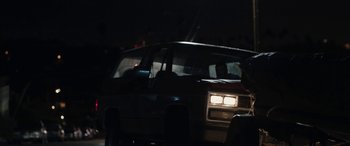 Movie still from “The Way Back” (2020), directed by Gavin O'Connor – A car driving down a street at night with headlights on; Medium shot, Over the shoulder angle