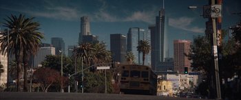 Movie still from “The Way Back” (2020), directed by Gavin O'Connor – A school bus driving down a street in front of tall buildings; Extreme Wide shot, High angle