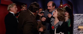 A man and a woman are being interviewed by a crowd of onlookers