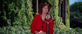Movie still from “The Way We Were” (1973), directed by Sydney Pollack – A woman in a red dress is standing next to a microphone; Medium shot, Low angle