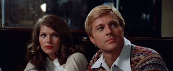 Movie still from “The Way We Were” (1973), directed by Sydney Pollack – A man and a woman sitting next to each other; Close Up shot, Low angle