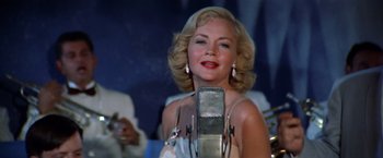 Movie still from “The Way We Were” (1973), directed by Sydney Pollack – A beautiful blonde woman with a microphone in front of her face; Close Up shot, Low angle