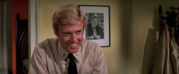 Movie still from “The Way We Were” (1973), directed by Sydney Pollack – A man in a white dress shirt and black tie smiling; Close Up shot, Over the shoulder angle