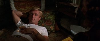 Movie still from “The Way We Were” (1973), directed by Sydney Pollack – A man laying on the ground in a living room; Medium shot, High angle