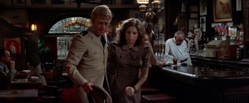 Movie still from “The Way We Were” (1973), directed by Sydney Pollack – A man and a woman are standing at a bar; Medium shot, Over the shoulder angle