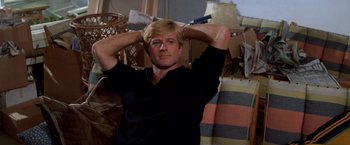 Movie still from “The Way We Were” (1973), directed by Sydney Pollack – A man in black shirt holding his hands behind his head; Medium shot, High angle