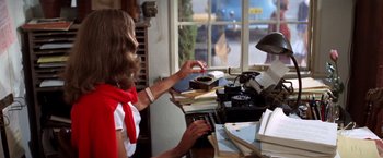Movie still from “The Way We Were” (1973), directed by Sydney Pollack – A woman typing at a typewriter in front of stacks of books; Medium shot, Over the shoulder angle