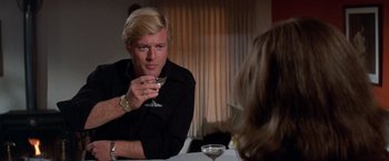 Movie still from “The Way We Were” (1973), directed by Sydney Pollack – A man sitting at a table with a drink in his hand; Close Up shot, Over the shoulder angle