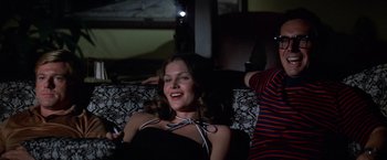 Movie still from “The Way We Were” (1973), directed by Sydney Pollack – A woman sitting on top of a couch holding a remote control; Medium shot, Low angle