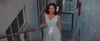 Movie still from “The Way We Were” (1973), directed by Sydney Pollack – A woman in a white dress standing next to a railing; Medium shot, High angle