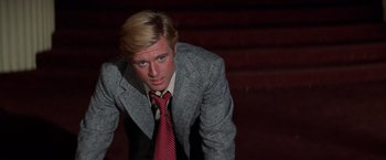 Movie still from “The Way We Were” (1973), directed by Sydney Pollack – A man in a suit and tie standing on some steps; Close Up shot, Low angle