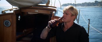 Movie still from “The Way We Were” (1973), directed by Sydney Pollack – A man is drinking a beer on a sailboat; Close Up shot, Low angle