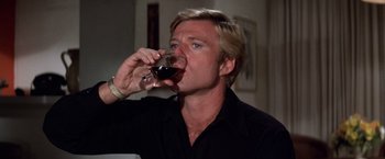 Movie still from “The Way We Were” (1973), directed by Sydney Pollack – A man drinking a glass of red wine from a wine glass; Close Up shot, Low angle