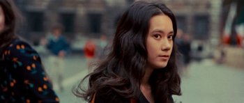 Movie still from “The Way of the Dragon” (1972), directed by Bruce Lee – A woman with long black hair standing on the street; Close Up shot, Over the shoulder angle