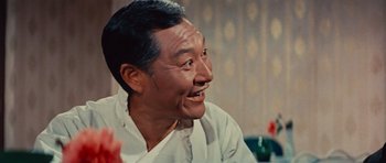 Movie still from “The Way of the Dragon” (1972), directed by Bruce Lee – An older man sitting in front of a table; Close Up shot, Low angle