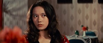 Movie still from “The Way of the Dragon” (1972), directed by Bruce Lee – A woman with long black hair wearing a black shirt; Close Up shot, Over the shoulder angle