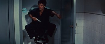 Movie still from “The Way of the Dragon” (1972), directed by Bruce Lee – A man is jumping in the air while holding a toothbrush; Wide shot, Overhead angle