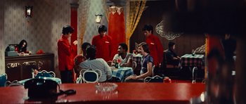 Movie still from “The Way of the Dragon” (1972), directed by Bruce Lee – A group of people sitting at a table in a restaurant; Wide shot, High angle