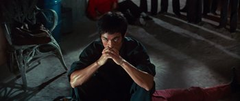 Movie still from “The Way of the Dragon” (1972), directed by Bruce Lee – A man sitting on the ground with his hands over his mouth; Medium shot, High angle