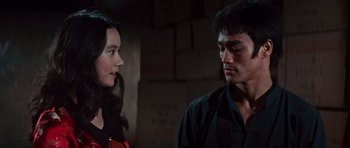 Movie still from “The Way of the Dragon” (1972), directed by Bruce Lee – A man and a woman standing next to each other in front of a brick wall; Close Up shot, Over the shoulder angle