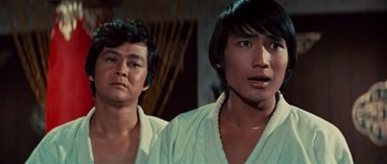 Movie still from “The Way of the Dragon” (1972), directed by Bruce Lee – Two asian men standing next to each other in a room; Close Up shot, Low angle