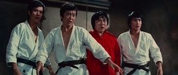 Movie still from “The Way of the Dragon” (1972), directed by Bruce Lee – A group of men standing next to each other in a room; Medium shot, Low angle