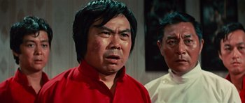 Movie still from “The Way of the Dragon” (1972), directed by Bruce Lee – A man in a red shirt and a man in a white shirt; Close Up shot, Low angle